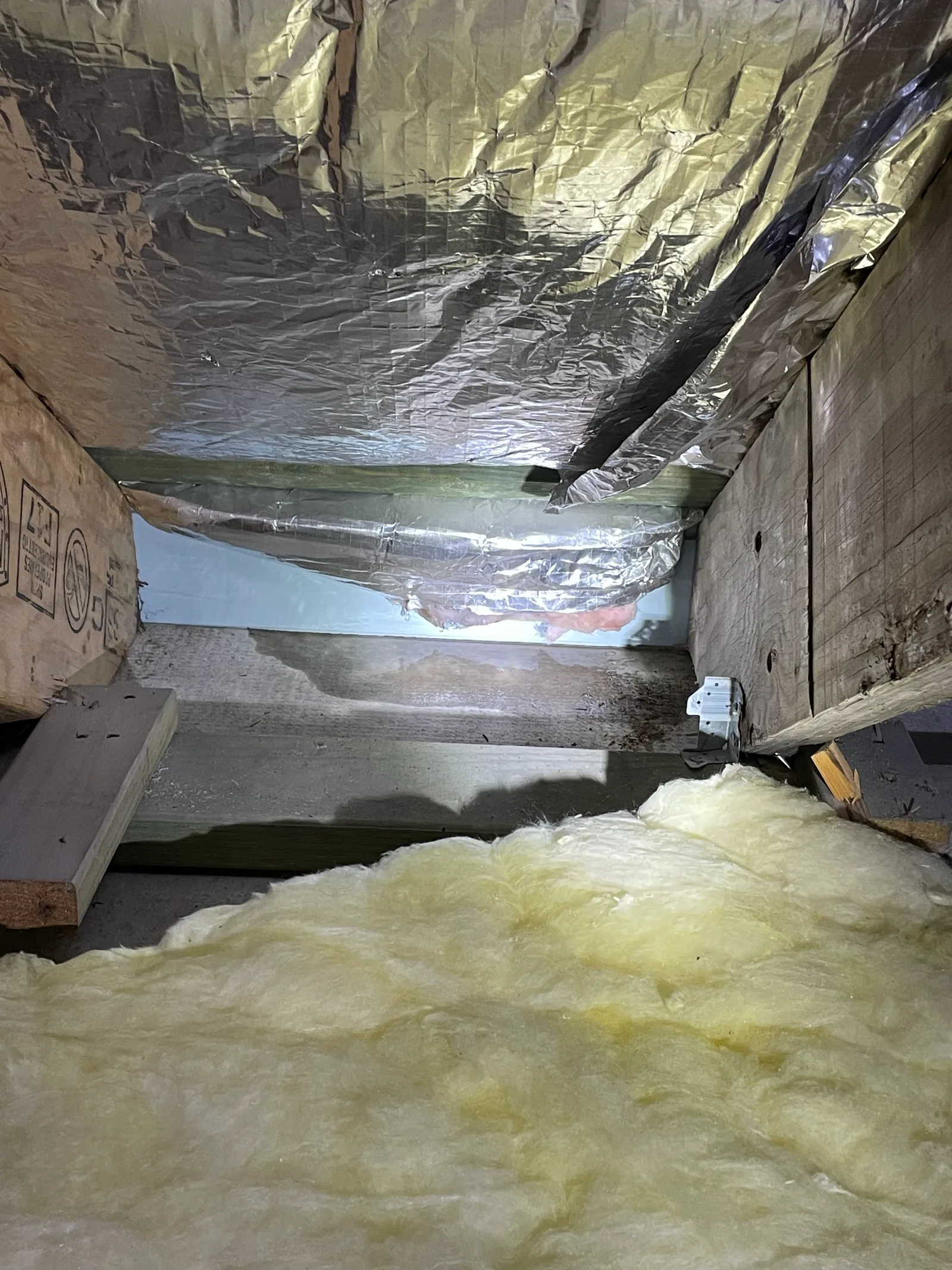 Roof space showing torn sarking and insulation batts left out of a section of ceiling above a bulkhead