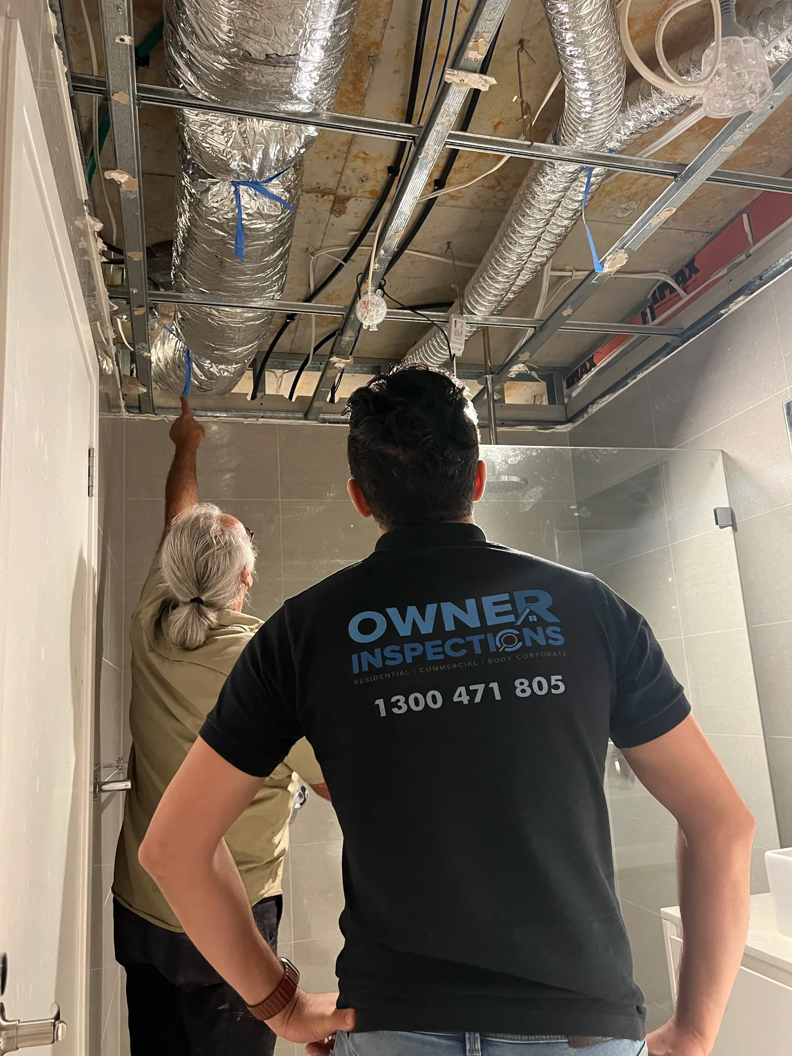 Owner Inspections inspector and builder reviewing exposed ceiling framing, ductwork and services in a bathroom before the ceiling is closed up
