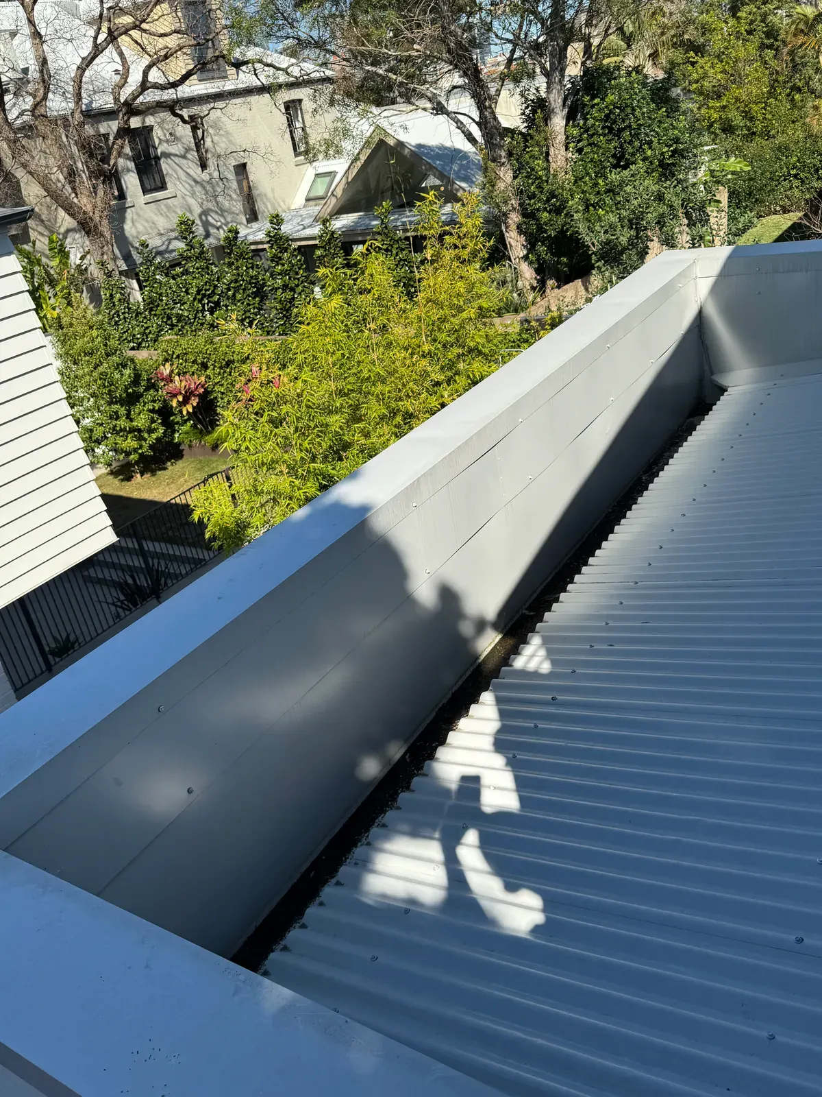 Metal roof apron flashing against a parapet wall with fixings spaced too far apart, recorded during a property inspection in Balmain NSW