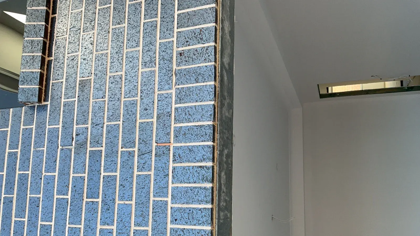 A face brick wall meeting a painted wall and ceiling, photographed during an inspection