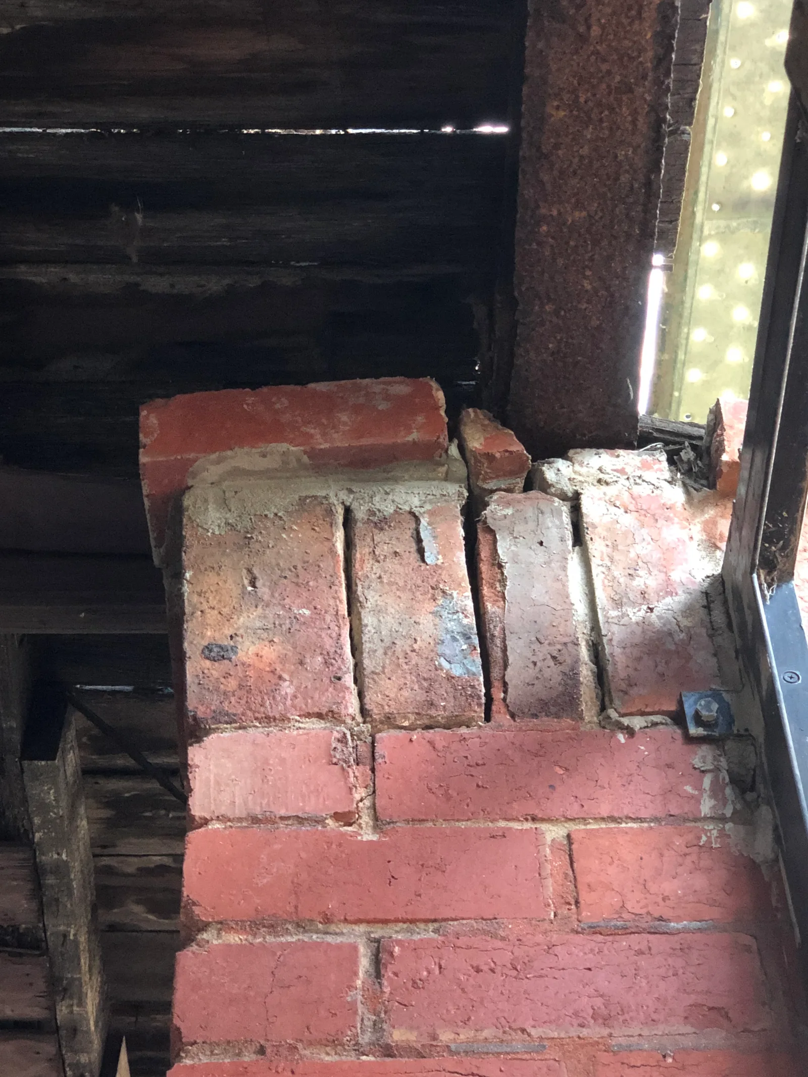 Cracked and displaced brickwork sitting on a rusted steel lintel above a subfloor void, recorded during a defect investigation