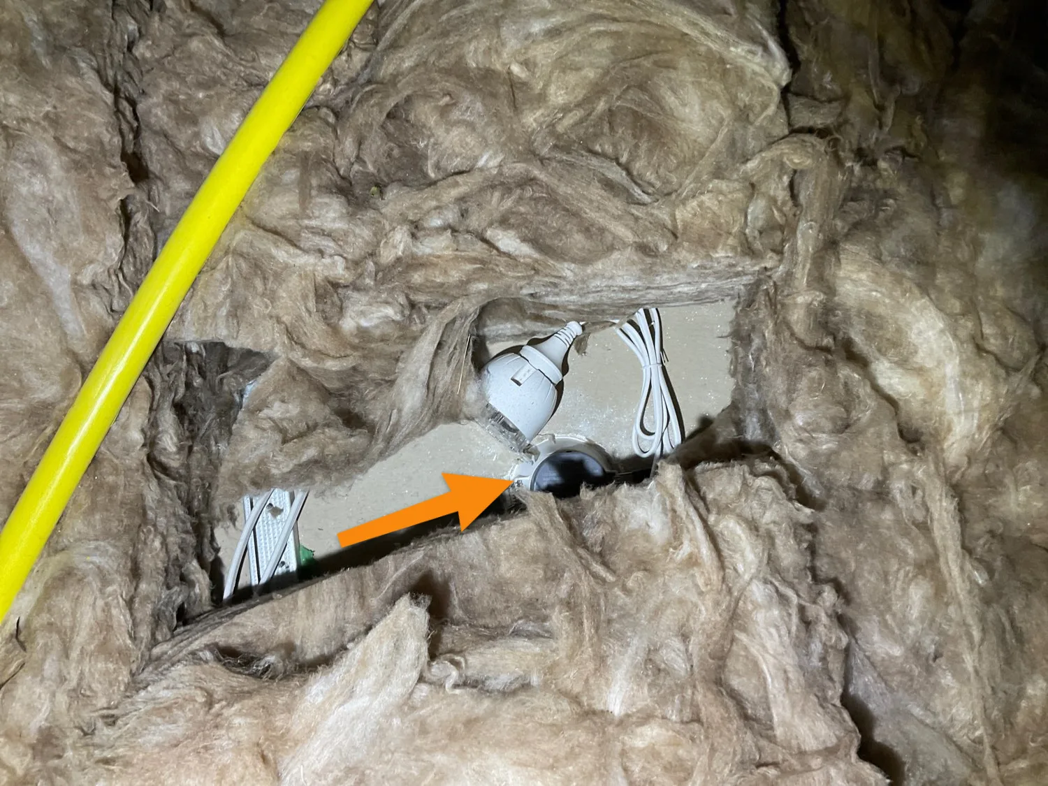 Ceiling batts pulled back around a fitting during an inspection, leaving a gap in the insulation