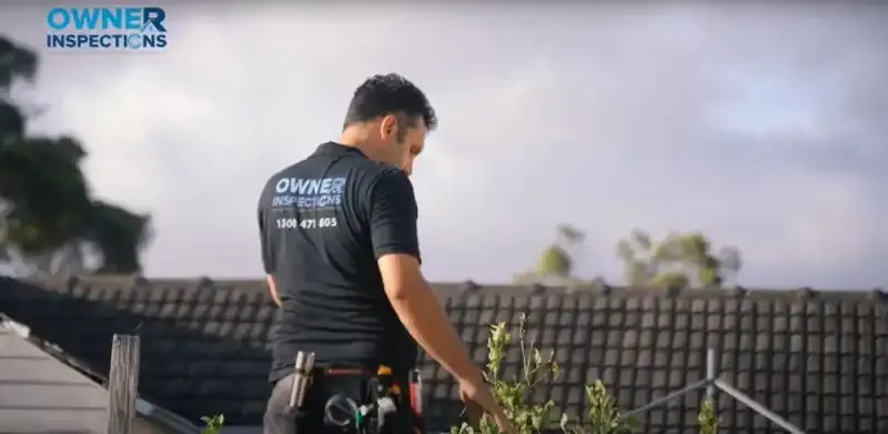 Property inspector assessing roof during rainy weather conditions in Australia