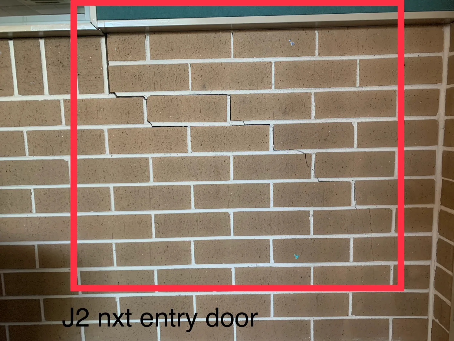 Annotated inspection photograph showing stepped cracking above a doorway, marked up for an insurance claim report