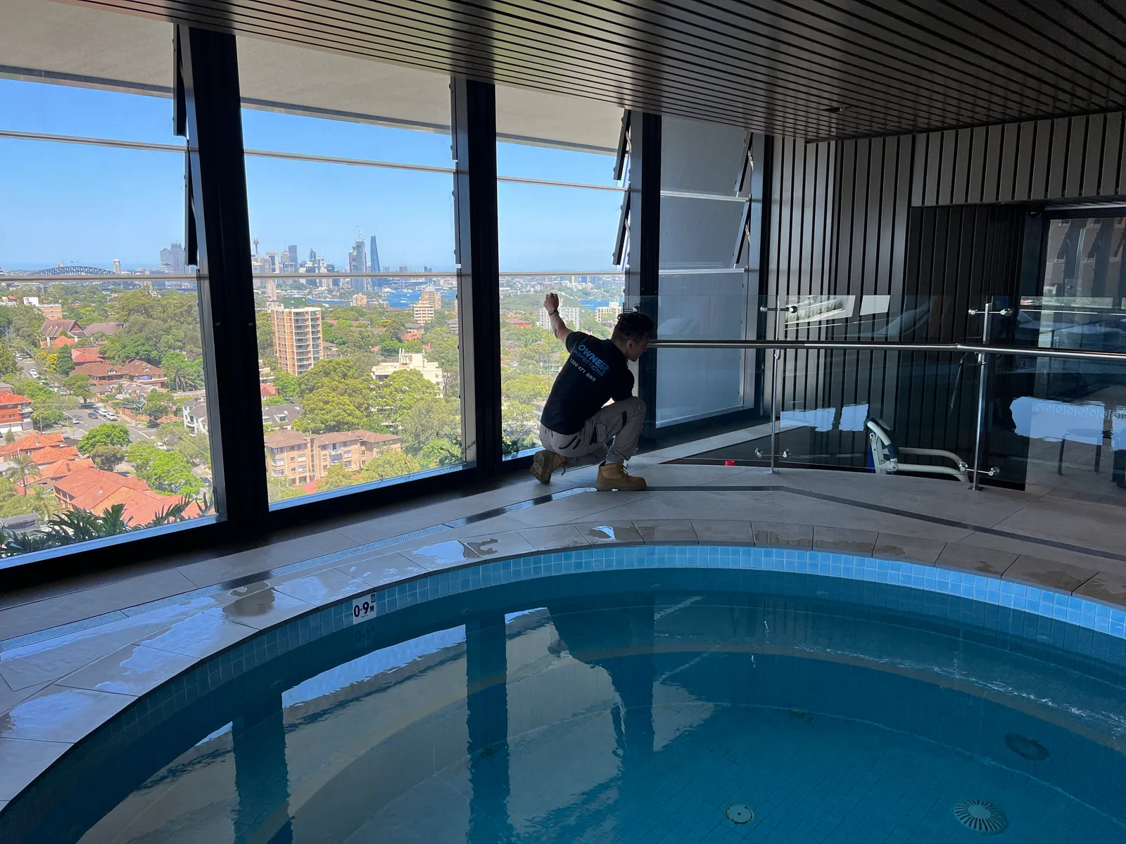 Owner Inspections inspector checking a glass pool barrier and the clear zone around it at an apartment pool