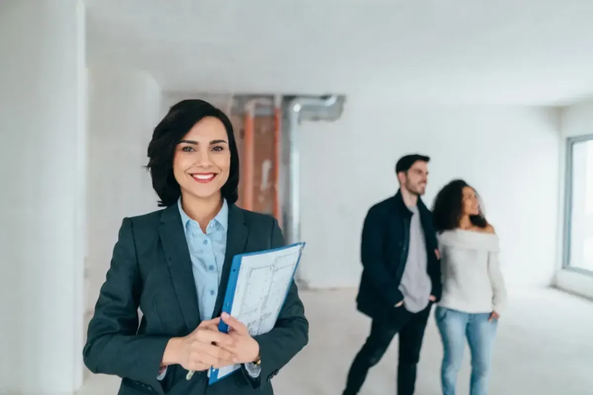Happy couple with real estate agent reviewing property before pre-settlement defect inspection in Australia