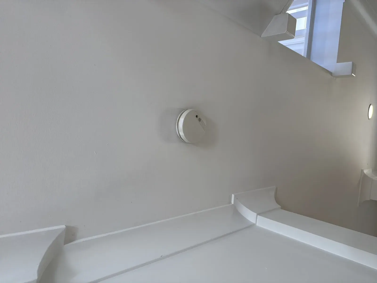 Smoke alarm on a rental ceiling tested with the test button