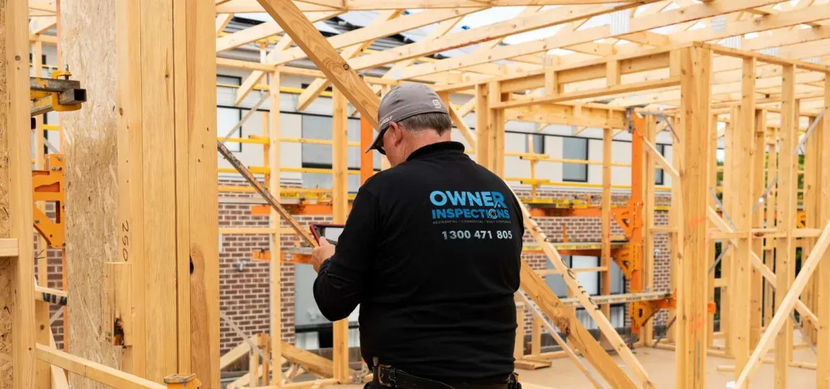 Building inspector examining timber framing on an Australian residential construction site during a frame stage inspection