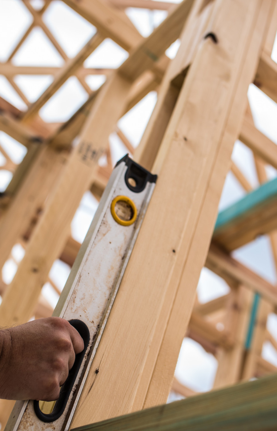 building inspector holding a spirit level against a timber frame on a house under construction