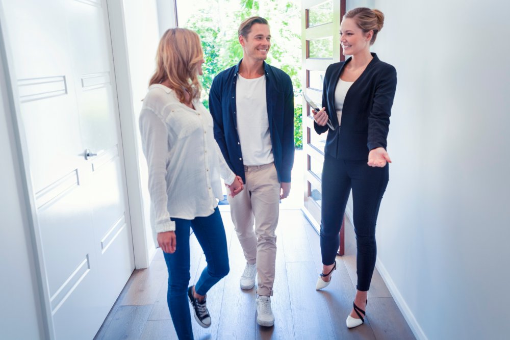 Real estate agent guiding a couple through a property, highlighting Pre-Purchase Inspections in Gold Coast.